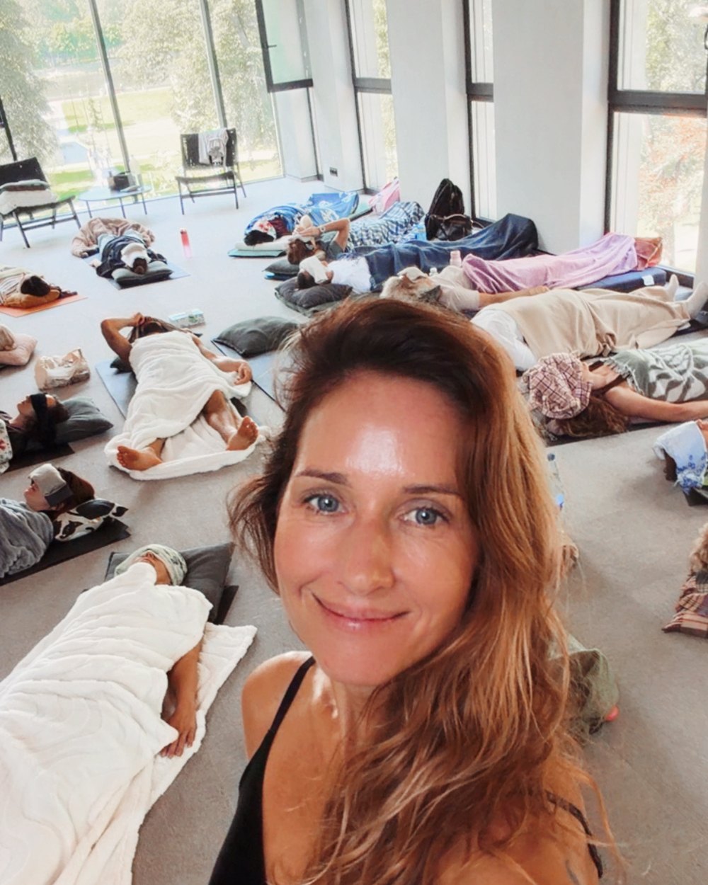 Violeta Druskinė salėje, už jos guli meditacijos dalyviai