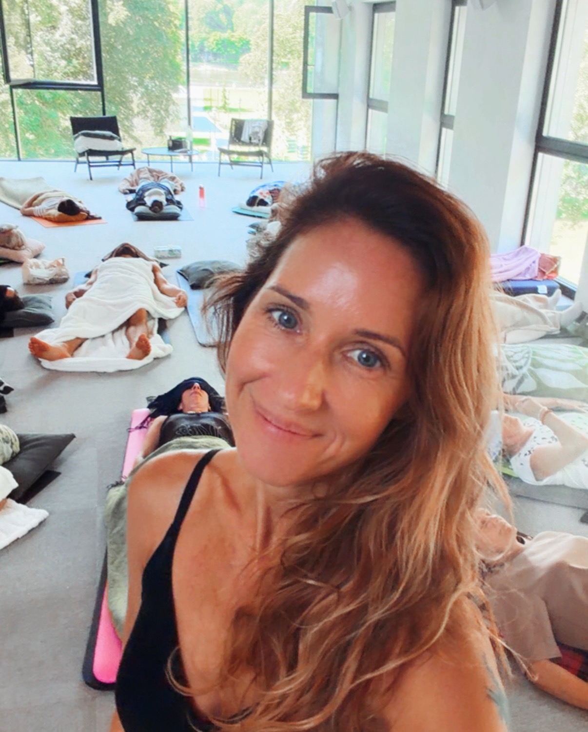 Violeta gyvos meditacijos salėje, fone – gulintys dalyviai